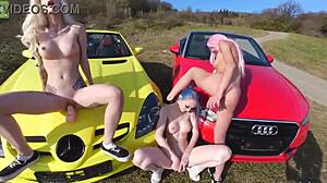 Three tattooed girls play with toys near cars.