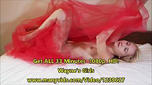 Odette cavorts on red bed playing with petite blonde pussy and natural tits