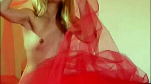 Odette cavorts on red bed playing with petite blonde pussy and natural tits