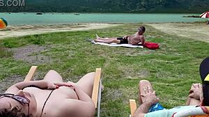 Tirkistelijä koskettelee itseään rannalla, kun vilauttelen vieressä