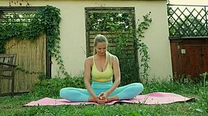 Sexy blonde does yoga in tight blue leggings on a lush green meadow.