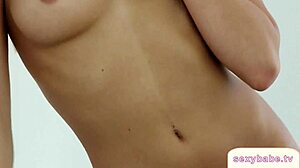 Hot blonde playboy babe strips clothes in bedroom revealing shaved pussy and tits for close-up tease.