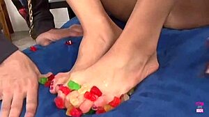 a kinky brunette dips feet in gummy bears for sticky footjob cumshot